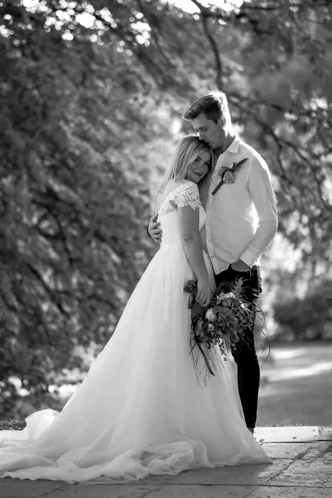 Svartvit bild med brudpar stående tätt intill varandra.