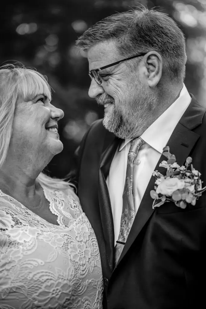 Brudpar i svartvitt som tittar på varandra.