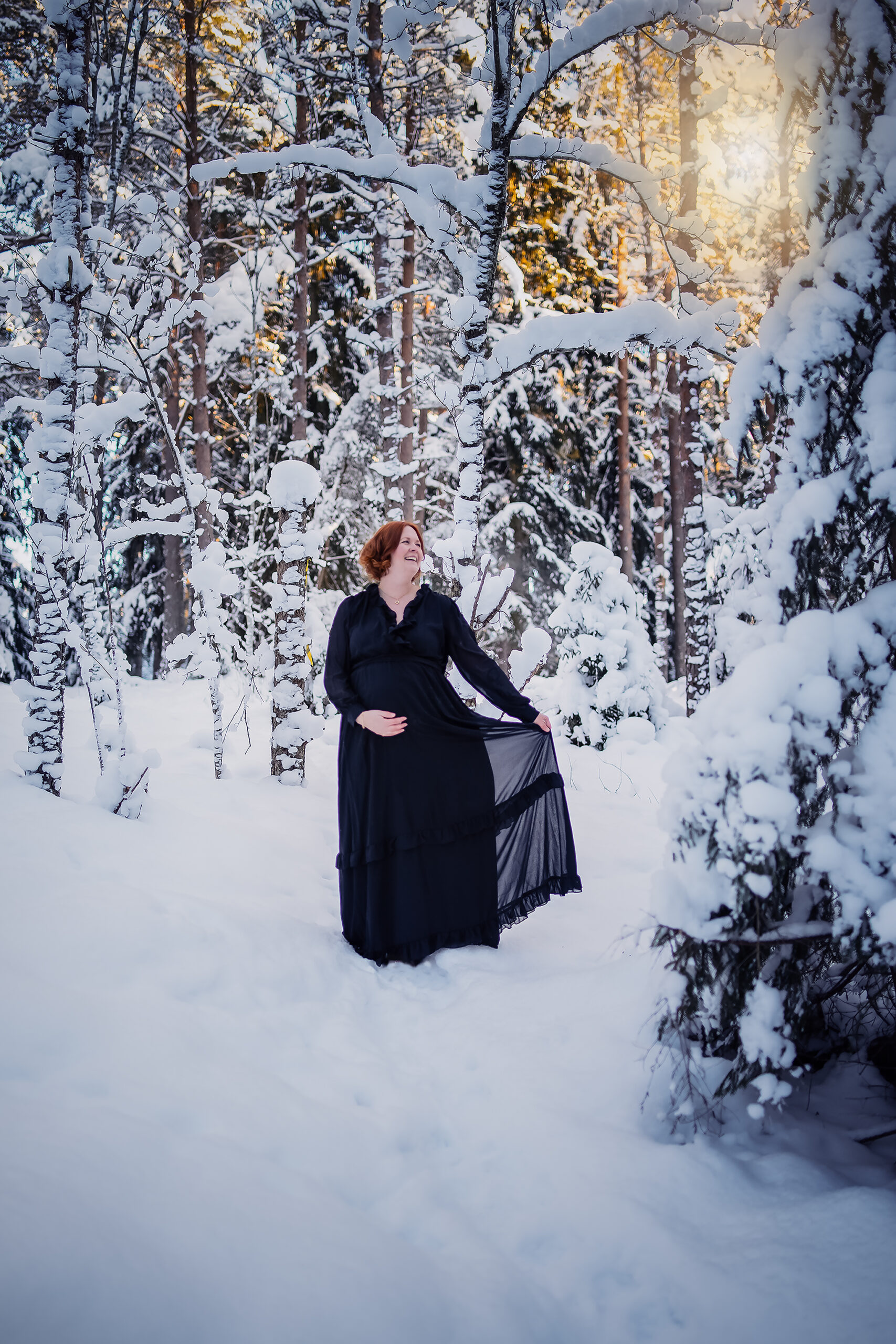 Gravid kvinna i svart klänning Kall vinterdag i skogen