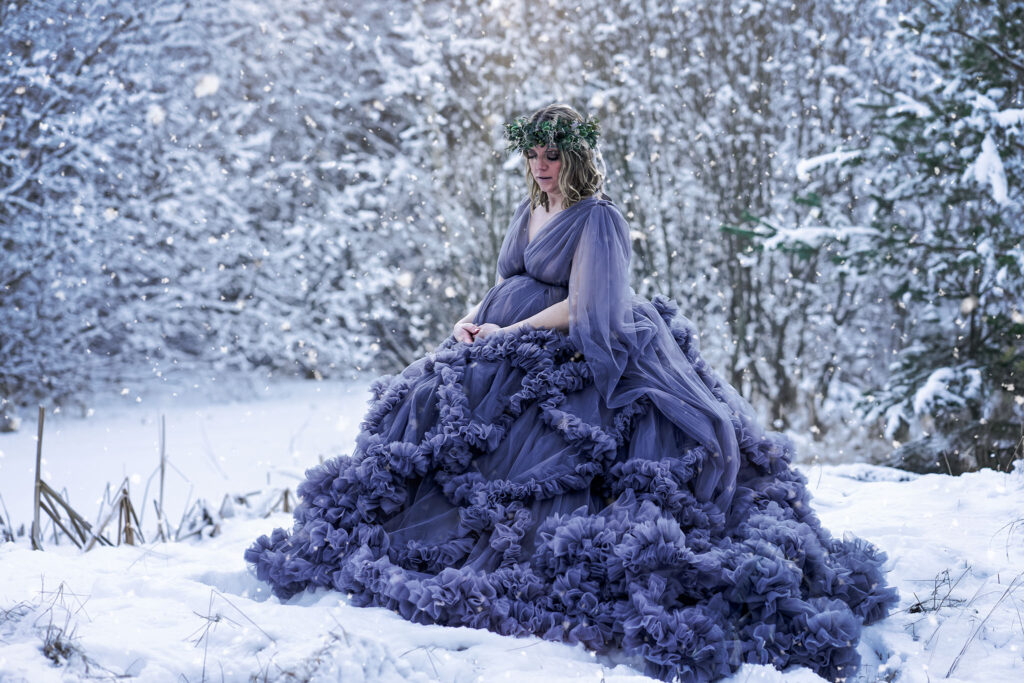 Vinterfotografering av gravid kvinna i blå tyllklänning