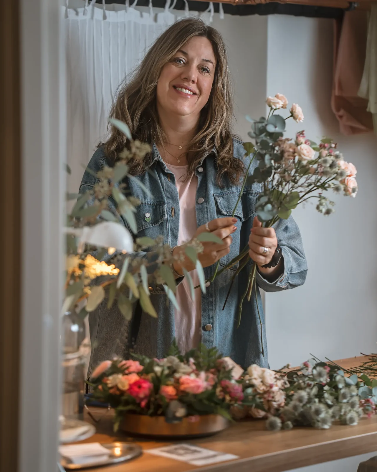 Florist i ateljé med säsongsblommor på arbetsbord